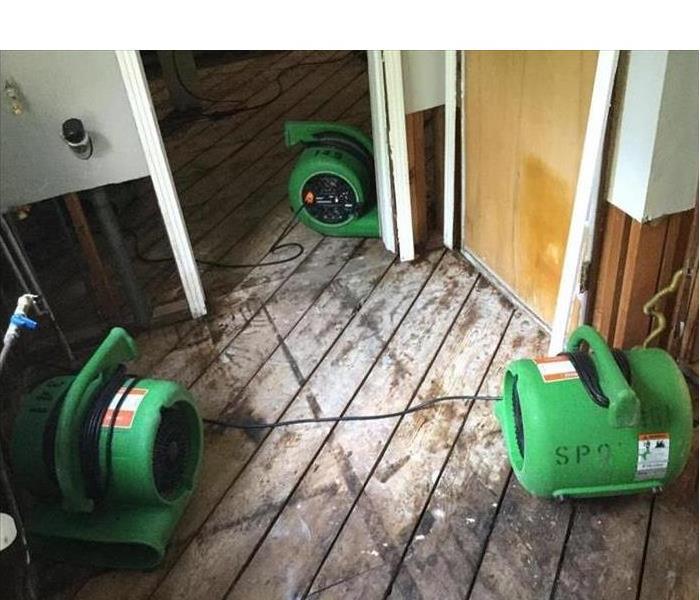old wood floor being dried out by several green SERVPRO machines 